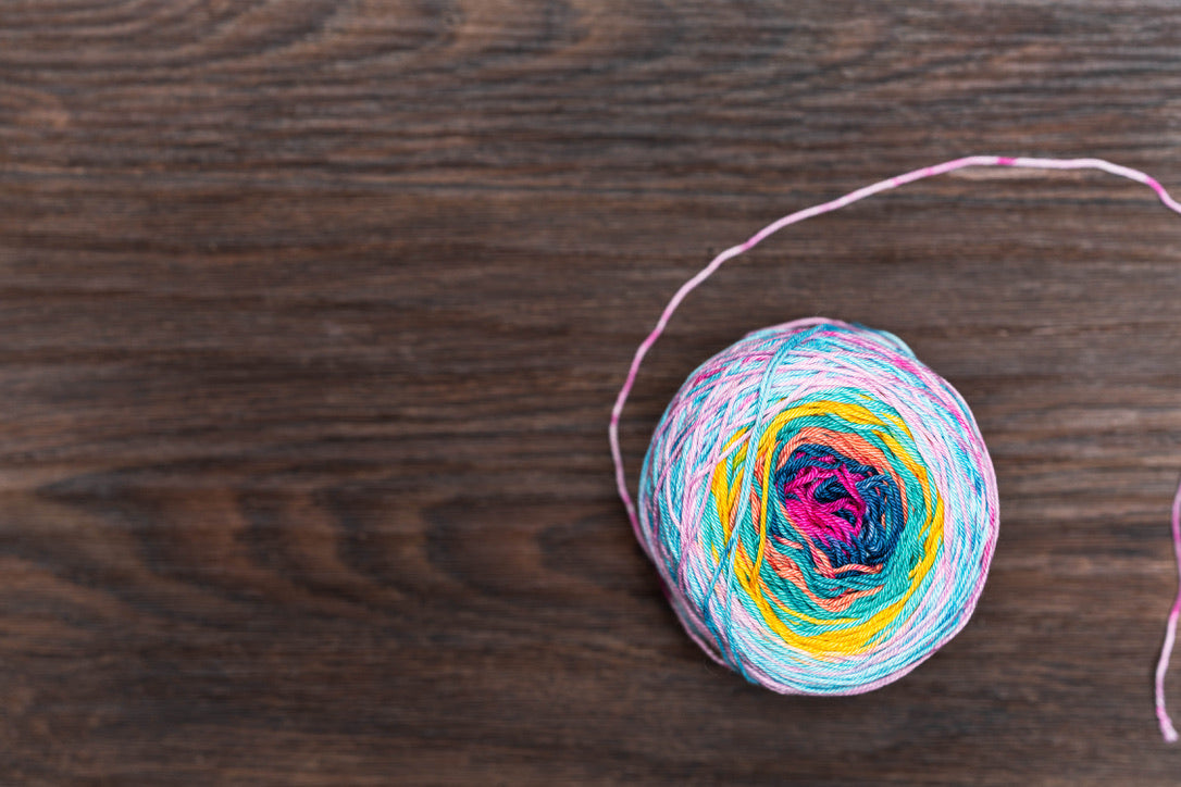 cake of rainbow yarn on wood table